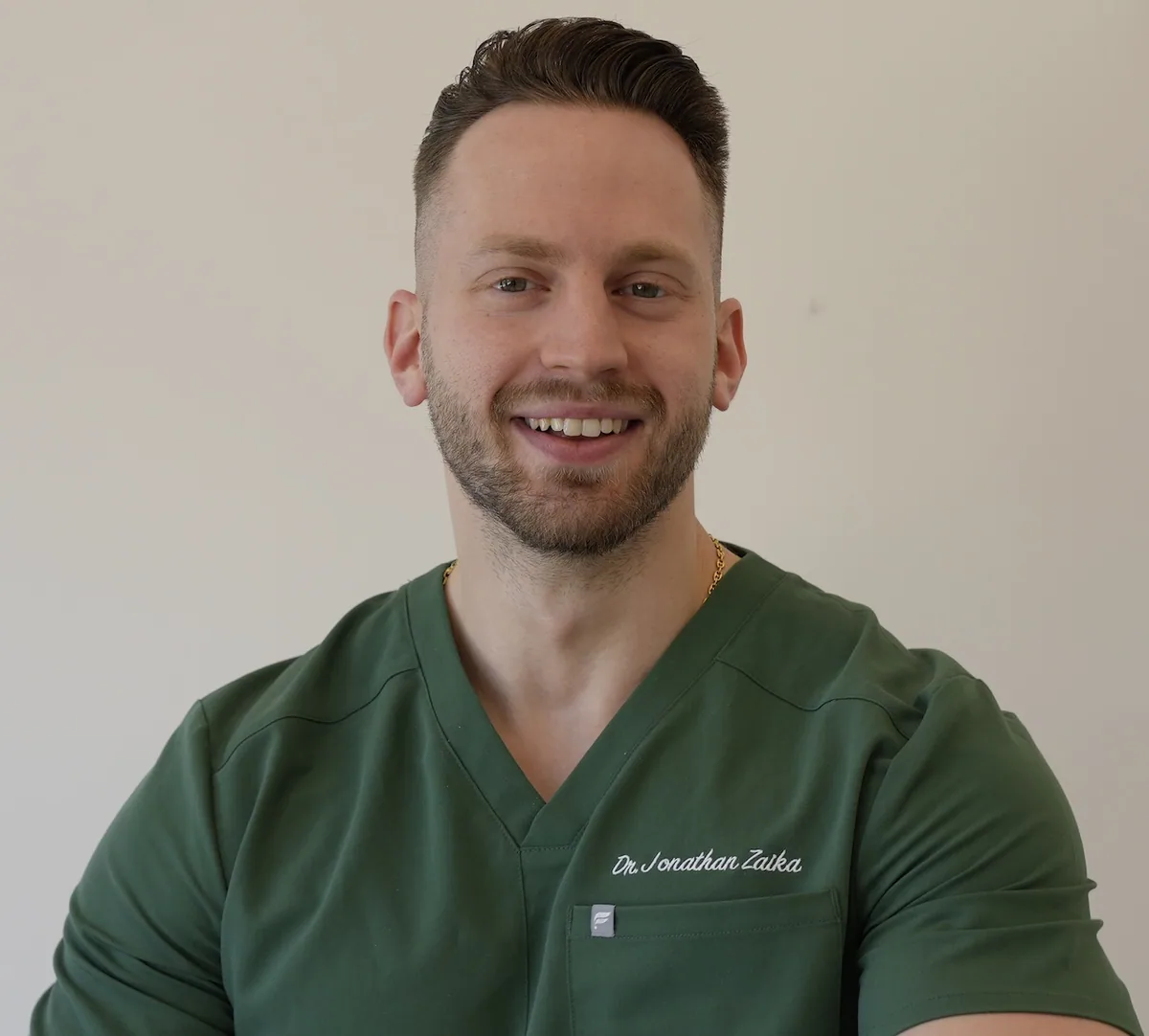 Dr. Jonathan Zaika, D.D.S., dentist at Modern Dental Hub, smiling in green scrubs