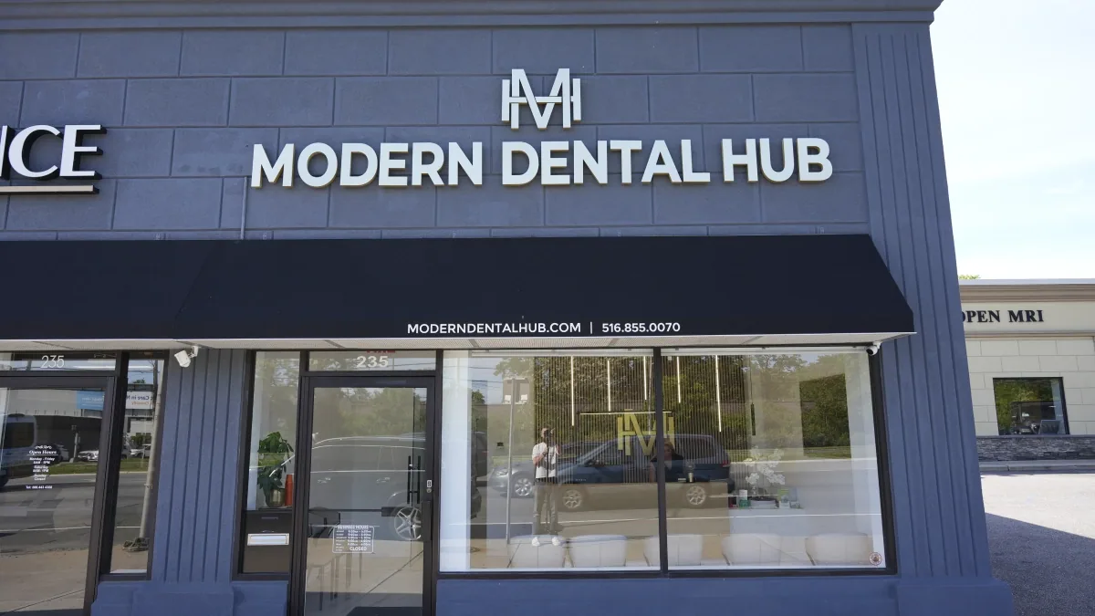 The Modern Dental Hub office at 235 Sunrise Highway in Merrick: grey facade, black awning and the gold monogram sign