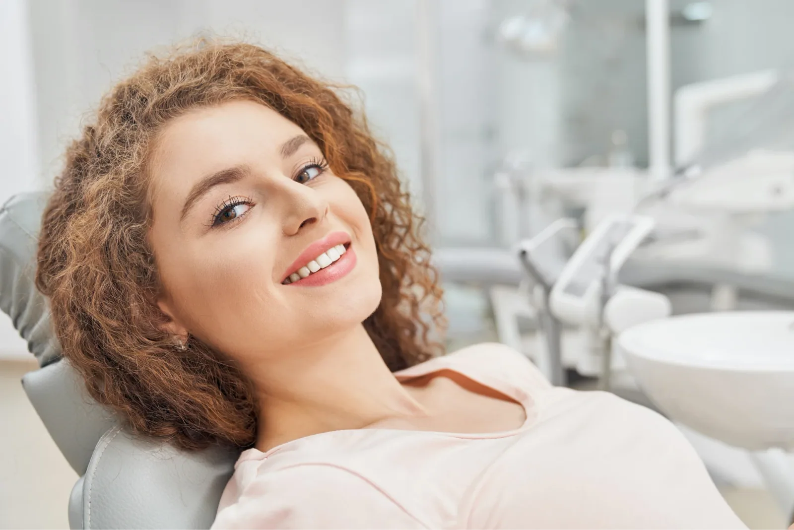 A smiling patient reclining in a dental chair (illustrative stock photo)