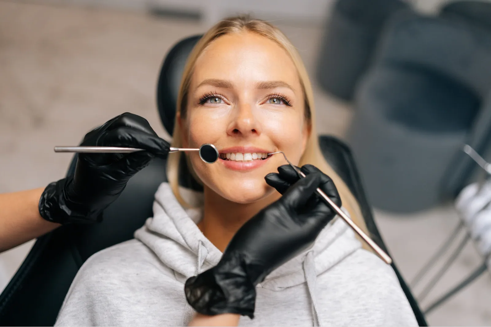 A patient smiling during a dental examination with a mirror and probe (illustrative stock photo)